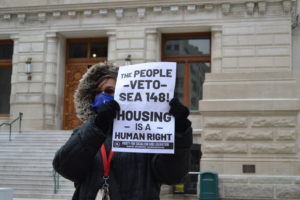 Doris Jones of the PSL holds up a banner that reads" The people VETO SEA 148"