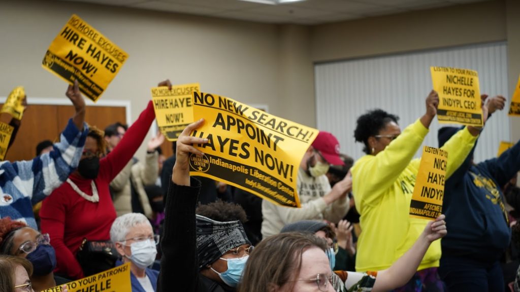 Angry patrons and community members hold signs reading "No New Search! Appoint Hayes Now!" and "Nichelle Hayes For IndyPL CEO!" Photo: Bryce Gustafson