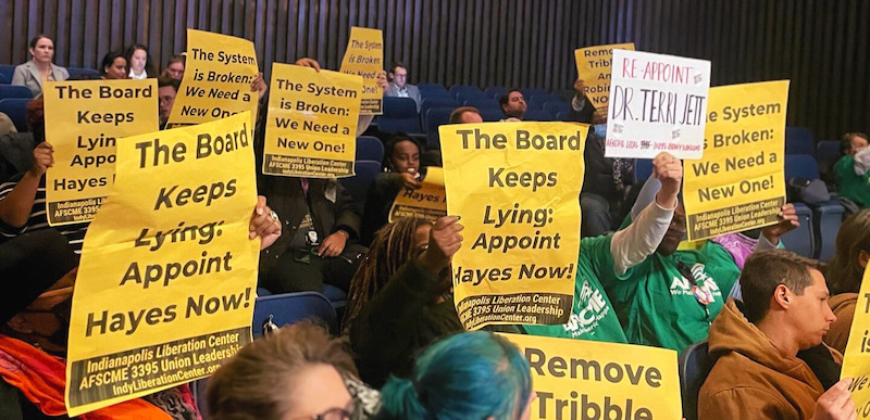 A group of people holding signs against the Board and for Hayes at the March IndyPL Board meeting.